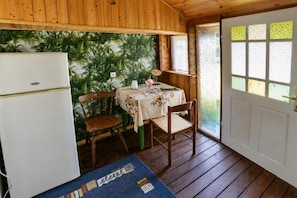Una cocina compacta con refrigerador, una mesa de comedor con sillas y una puerta con ventana.