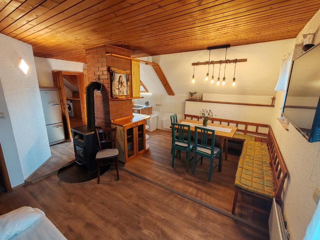 A cozy room with a wooden ceiling, a dining table with chairs, a fireplace, and a bed.