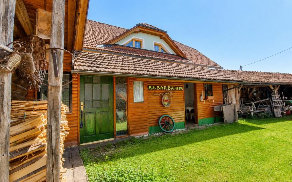 A wooden building with a green door, a sign reading 'BARBA,' and a wheel outside.