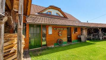 A wooden building with a green door, a sign reading 'BARBA,' and a wheel outside.