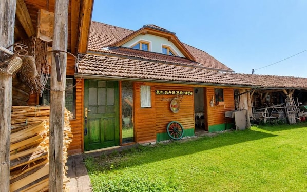 A wooden building with a green door, a sign reading 'BARBA,' and a wheel outside. - Apartment Ursa Major & Glamp Barba (Preddvor)