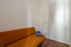 A room with a sofa, a door, and a small trash bin. - GuestHost - Modern and Bright Apartment in Rome (Rome)