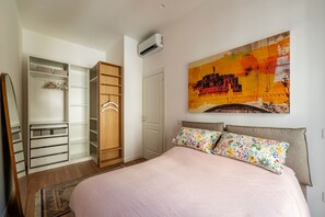 A bedroom with a bed, a wardrobe, and a large painting on the wall. - GuestHost - Modern and Bright Apartment in Rome (Rome)
