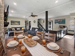 A modern living room with a dining area, a kitchen, and a staircase. - Across from Lazy River | Hot Tub | 6BR (Hollister)