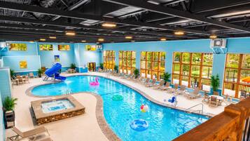 Une piscine intérieure dotée d’un jacuzzi, de chaises longues et d’un toboggan.