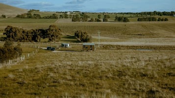 A rural landscape with a fenced field, a small building, and a vehicle.
