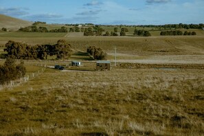Un paysage rural avec un champ délimité par une clôture, un petit bâtiment et un véhicule.
