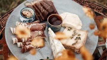 Una mesa redonda con una variedad de quesos y embutidos, junto a pequeños recipientes con salsas.