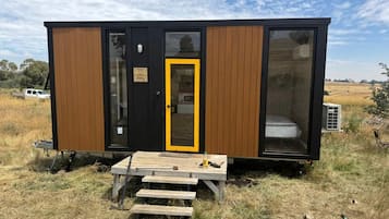 A small cabin with a wooden exterior, a yellow door, and a bench outside.