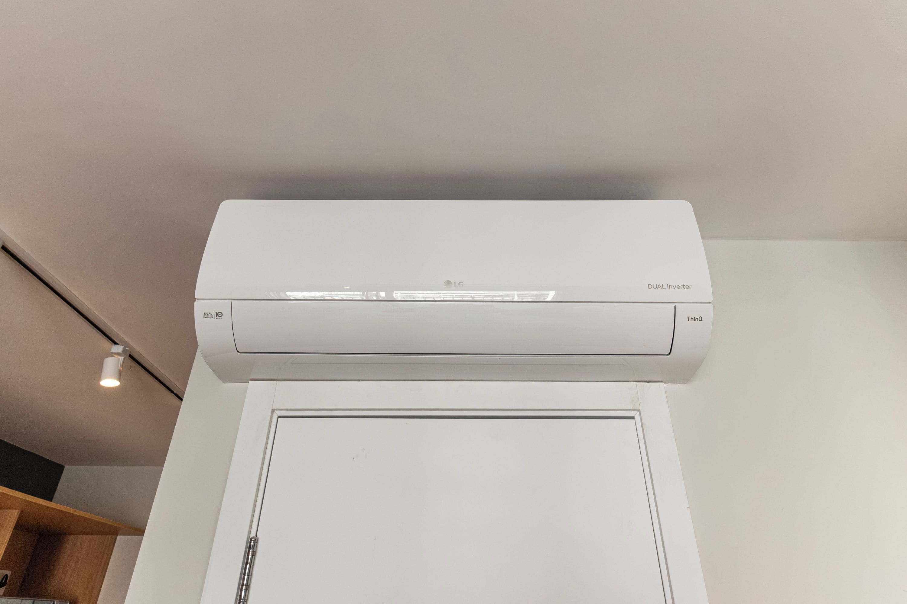 Ar condicionado branco fixado na parede acima de uma porta branca.