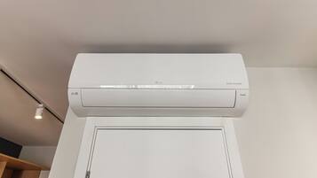 Ar condicionado branco fixado na parede acima de uma porta branca.