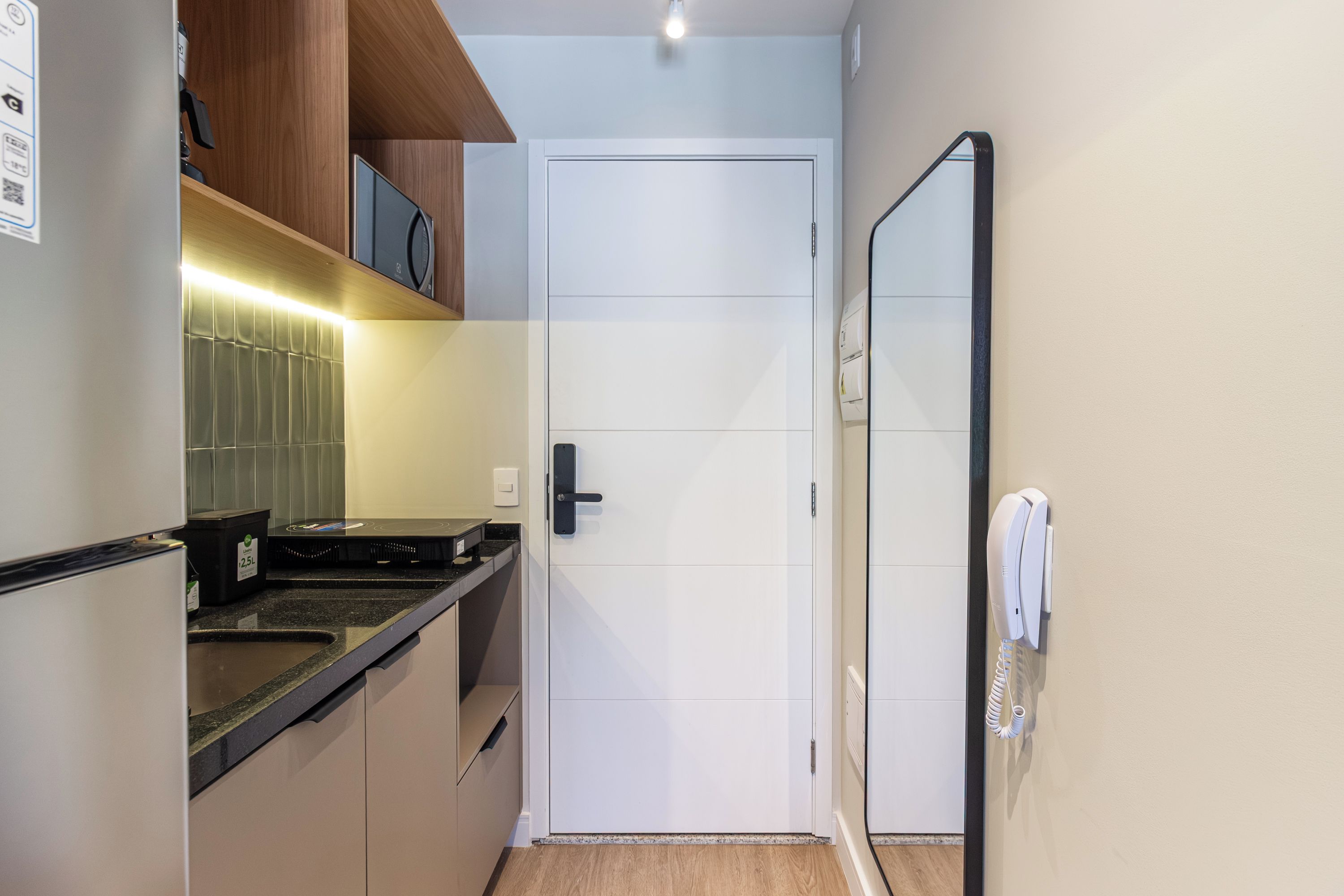Una cocina compacta con microondas, horno empotrado y una pequeña encimera.