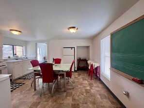 Una cocina moderna con comedor, refrigerador y pared con pizarra.