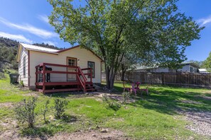 A single-story house with a red porch, a small yard, and a wooden fence.
