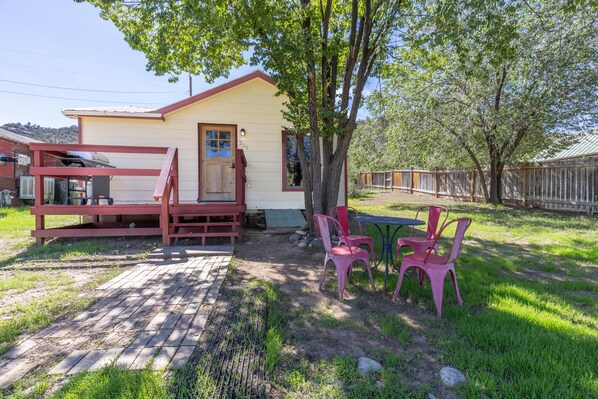 A small house with a porch, a table, and chairs outside.
