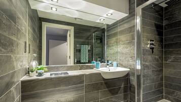 Un baño moderno con un espejo grande, un lavabo y una zona de ducha.