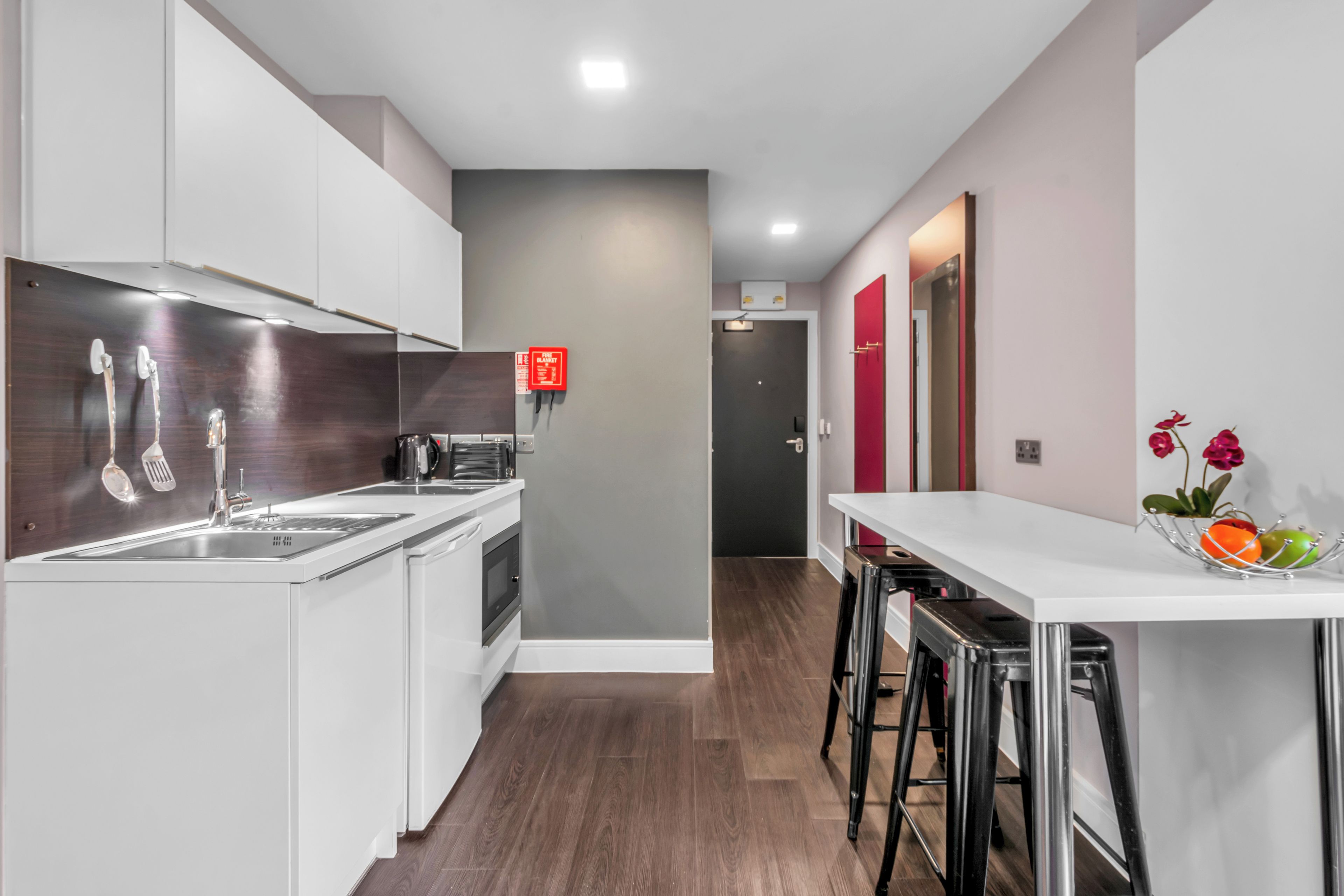 Una cocina moderna con armarios blancos, electrodomésticos de acero inoxidable y un letrero rojo de seguridad contra incendios.