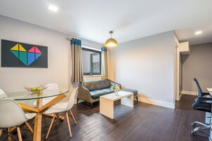 Un salon moderne avec une table à manger en verre, un canapé et une table basse.