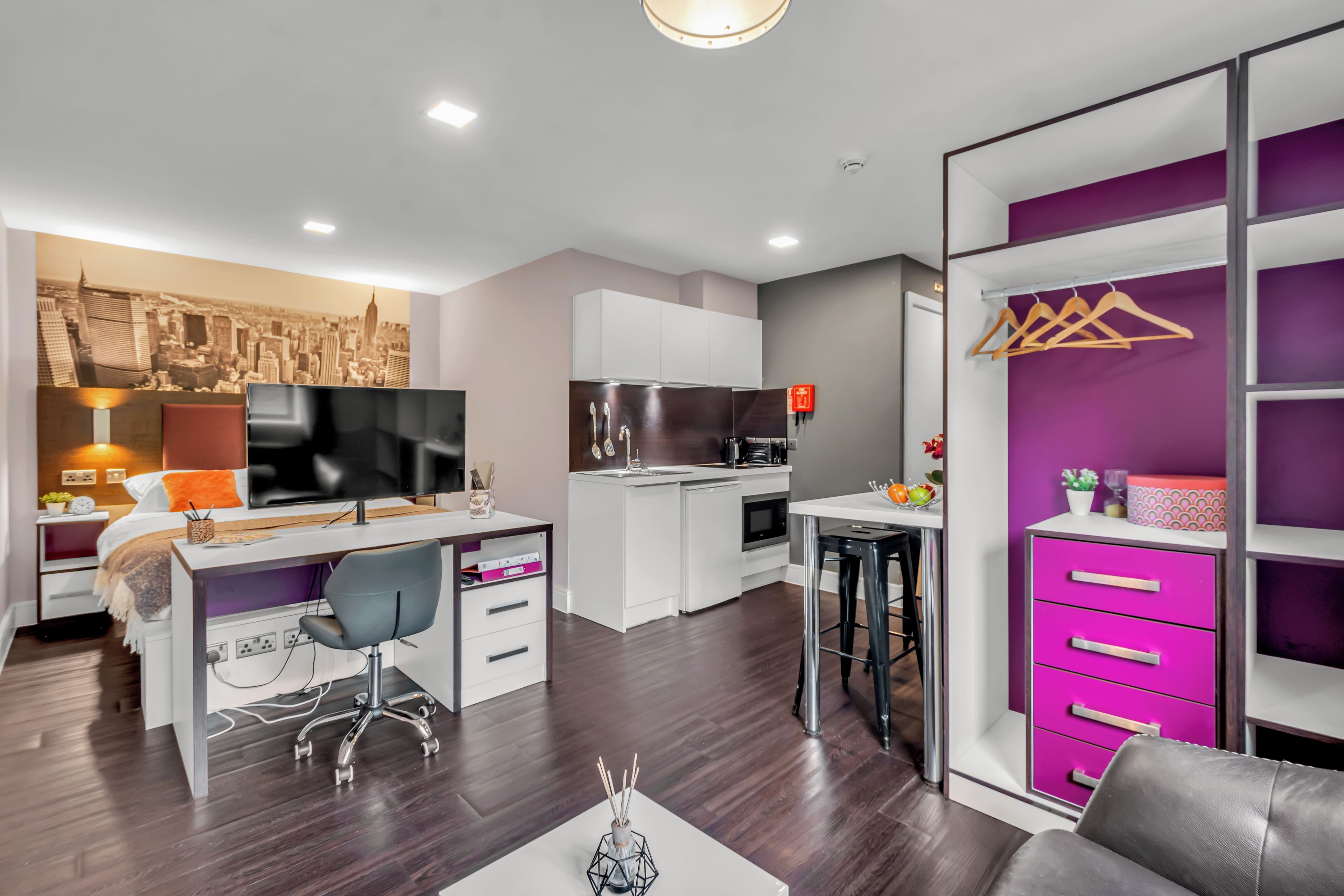 A modern bedroom with a bed, bedside table, and a cityscape wall art.