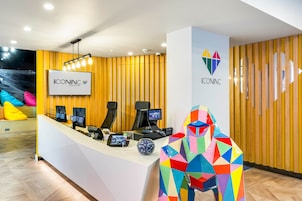 Un comptoir d’accueil doté de plusieurs écrans d’ordinateur, d’un logo et d’une sculpture géométrique aux couleurs vives.