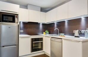 Cozinha moderna com eletrodomésticos embutidos, micro-ondas, forno e lava-louças.