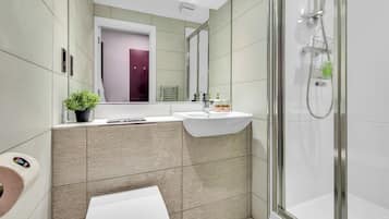 A modern bathroom with a glass shower enclosure, a white sink, and a toilet.