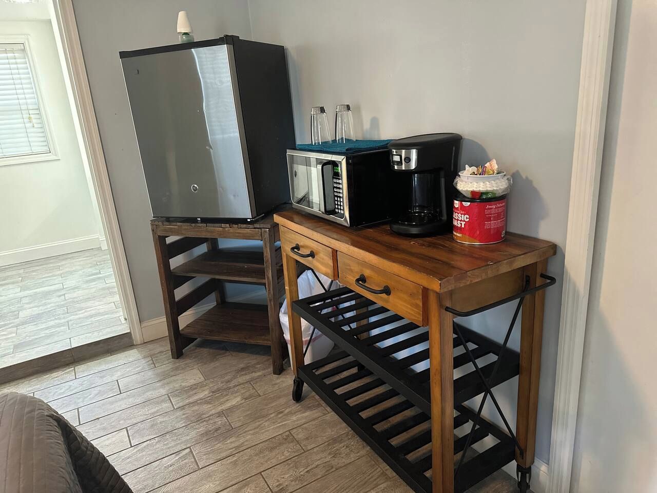 Uma cozinha compacta com micro-ondas, cafeteira e uma lata de café.