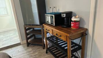 Uma cozinha compacta com micro-ondas, cafeteira e uma lata de café.