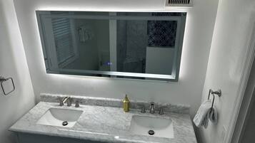 A bathroom with a double sink vanity, a large mirror, and a towel rack.