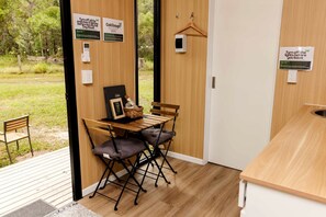 Ein kleines Zimmer mit einem Holztisch und -stühlen, einer kleinen Hängelampe und einer Tür, an der ein Schild angebracht ist, das darauf hinweist, das Licht vor dem Verlassen auszuschalten.