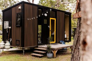 A compact, modern cabin with a wooden exterior, a yellow door, and a small deck area. - Cozy Tiny House Retreat with Firepit & Bush Views in Round Hill, Australia (Round Hill)