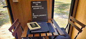 A wooden bench with a welcome sign, a book, and a notebook on it.