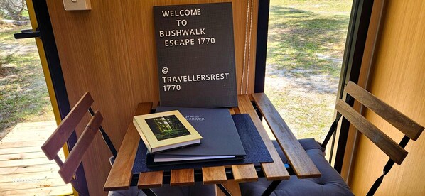 A wooden bench with a welcome sign, a book, and a notebook on it.