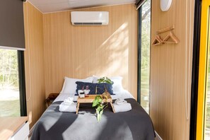 Ein modernes Schlafzimmer mit Bett, Nachttisch und Fenster.
