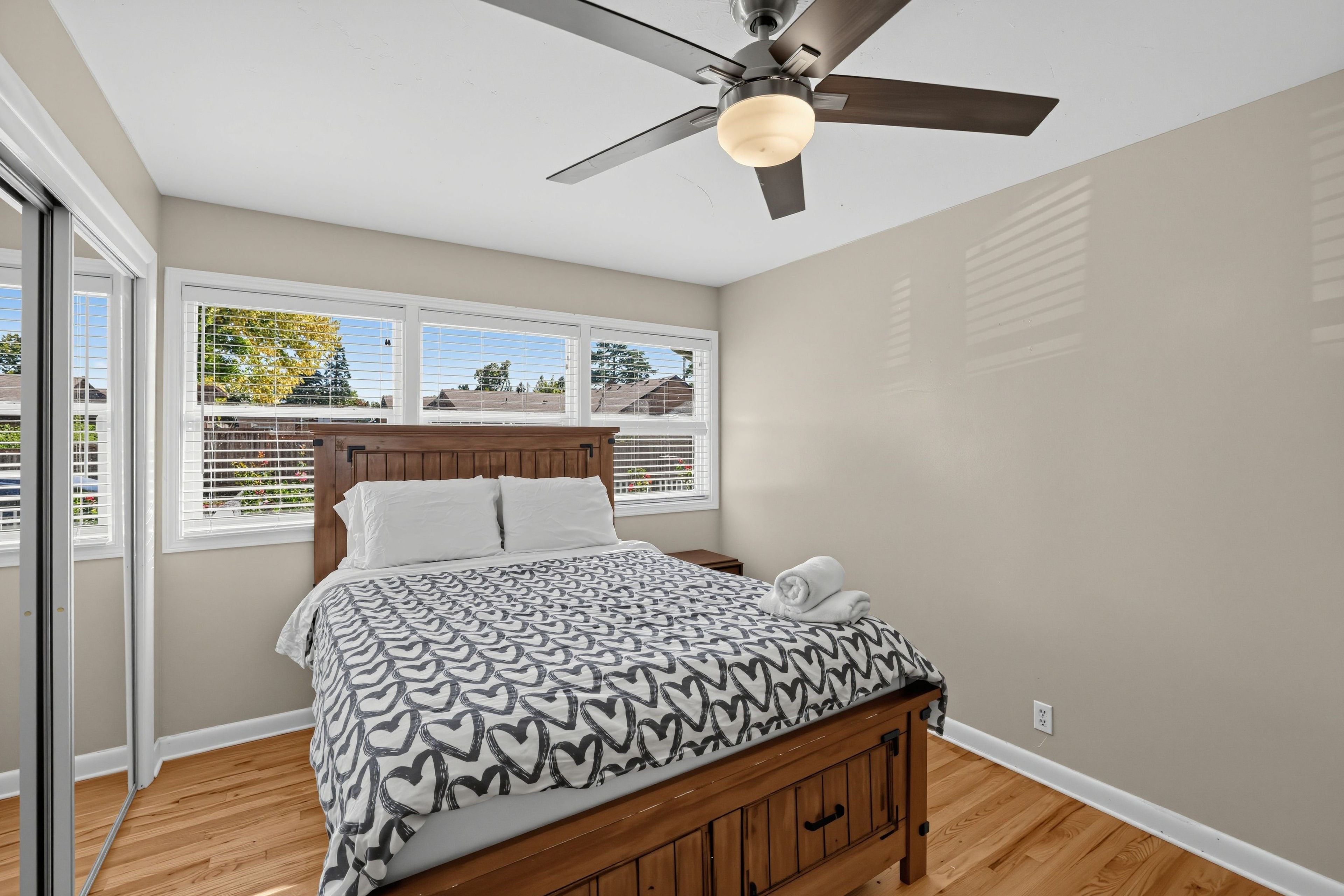 Un dormitorio con cama, ventilador de techo y ventana con persianas.