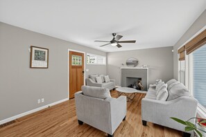 Una sala de estar moderna con chimenea, sofás grises y un ventilador de techo.