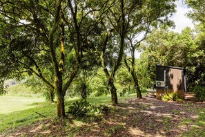 A rustic cabin with a wooden deck, surrounded by lush greenery and trees.