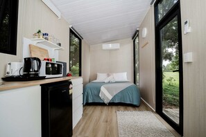 Una habitación compacta con cama, kitchenette y ventanas amplias.