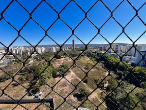 A chain-link fence with a view of a cityscape, including buildings and a hill in the background. - CRCN - Amethist Tower (Caldas Novas)