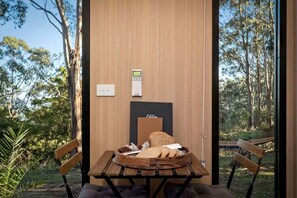 A room with a wooden table, two chairs, a bench, a small table with bread, and a thermostat on the wall.