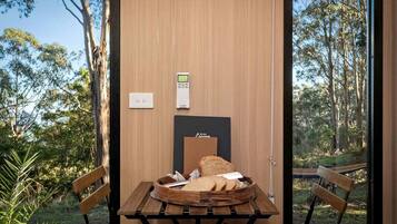 Une pièce avec une table en bois, deux chaises, un banc, une petite table avec du pain et un thermostat fixé au mur.