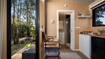 Une cuisine moderne avec des meubles en bois, un coin repas avec un banc et une vue sur l’extérieur.