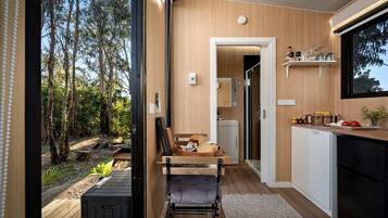 Une cuisine moderne avec des meubles en bois, un coin repas avec un banc et une vue sur l’extérieur.