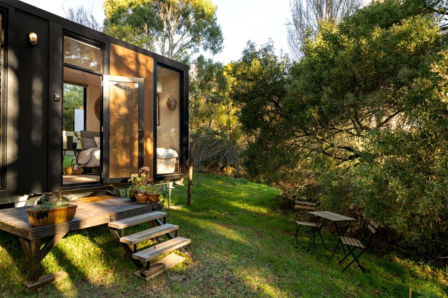 A modern outdoor seating area with a wooden deck, benches, and potted plants.