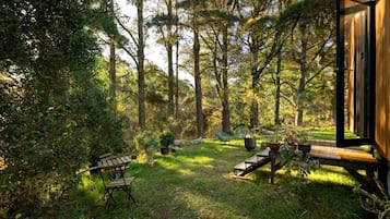 A wooden deck with outdoor furniture, surrounded by dense forest.