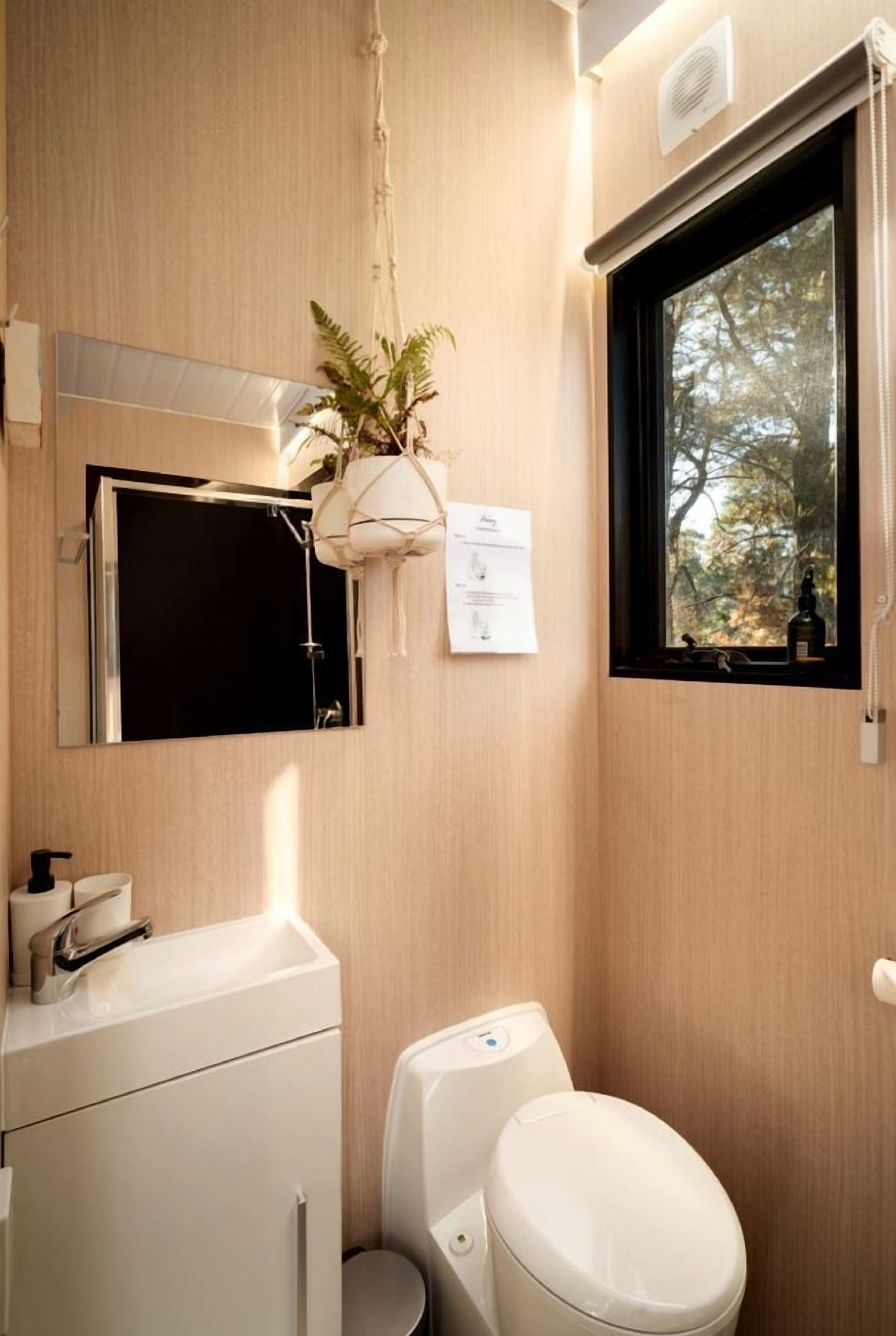 A compact bathroom with a toilet, sink, and a mirror above the sink.