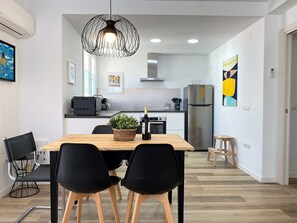 A modern kitchen with a dining area, a black chandelier, and a refrigerator. - Apartment in Nerja Near Torrecilla Beach (Nerja)