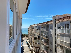 A multi-story residential building with balconies, a clear sky, and a view of the sea. - Apartment in Nerja Near Torrecilla Beach (Nerja)