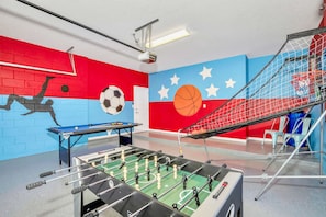 A room with a foosball table, a ping pong table, and a basketball hoop. - Waterfront Family Mansion w BBQ, Games Room & Pool (Kissimmee)