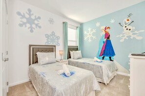 Une chambre avec deux lits, une table de chevet, une commode et un mur décoré de motifs en forme de flocons de neige.